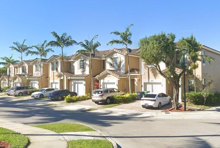 a front view of residential houses with yard and tree