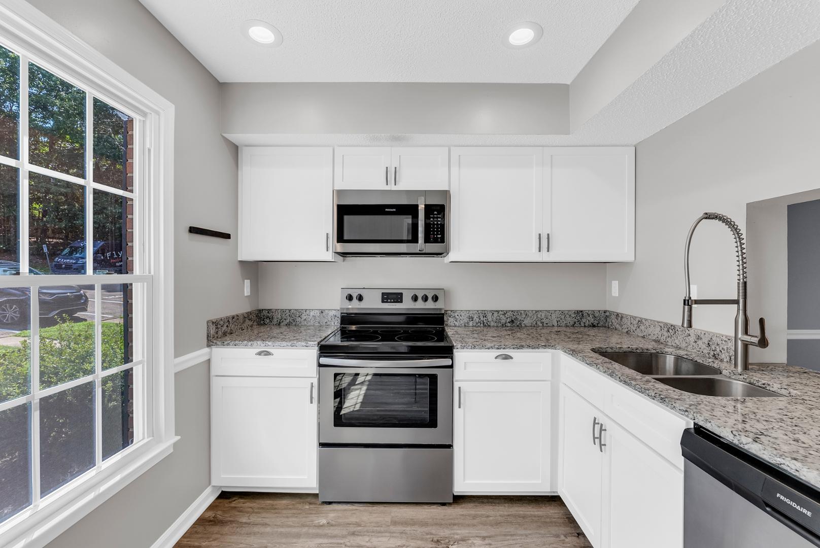 a kitchen with granite countertop white cabinets and appliances