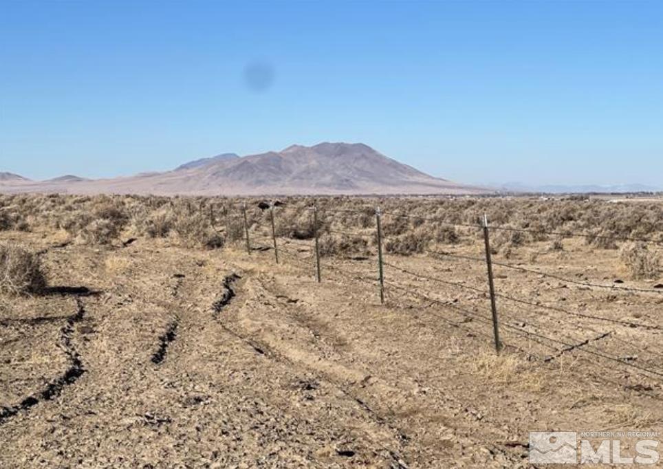 a view of a dry yard with mountains in the background