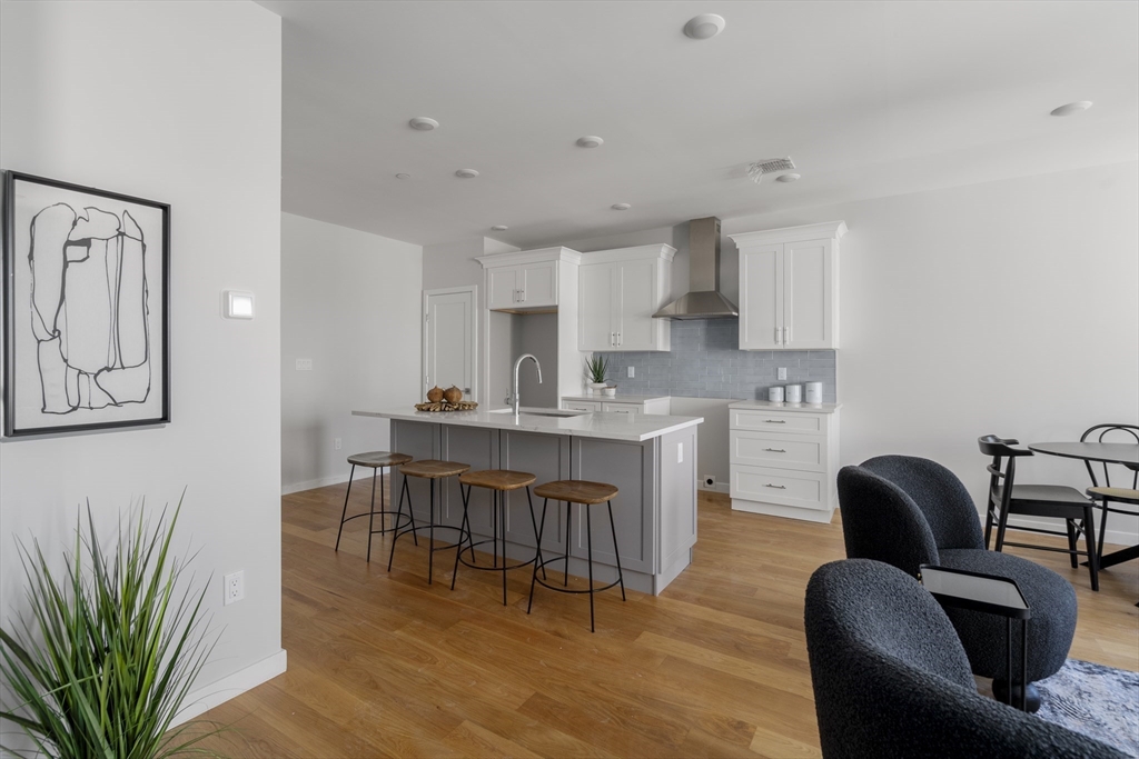 a living room with furniture dining table wooden floor and a kitchen view