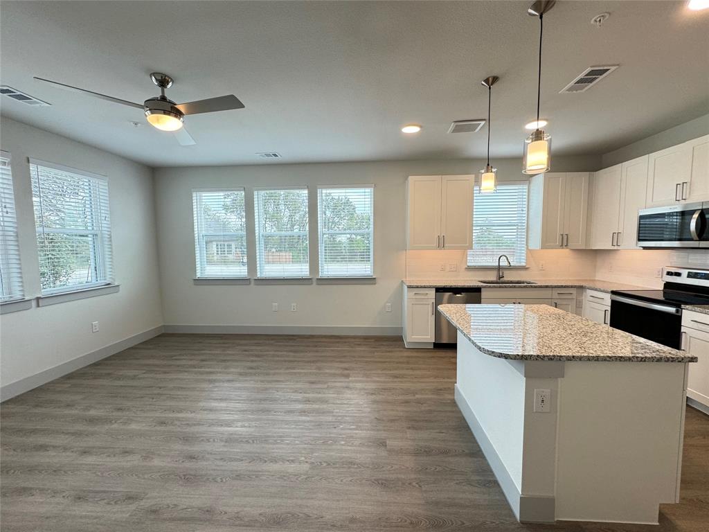 a kitchen with kitchen island granite countertop a sink appliances cabinets and a counter top space