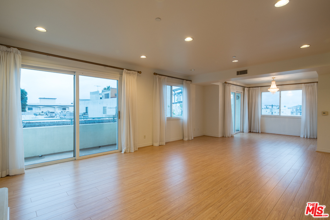 a view of an empty room with window and wooden floor