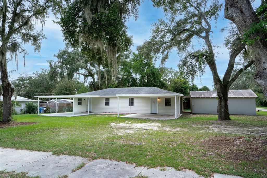 a view of a house with a yard deck and a large tree