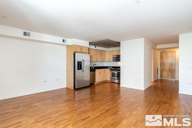 a kitchen with stainless steel appliances wooden floor and a refrigerator