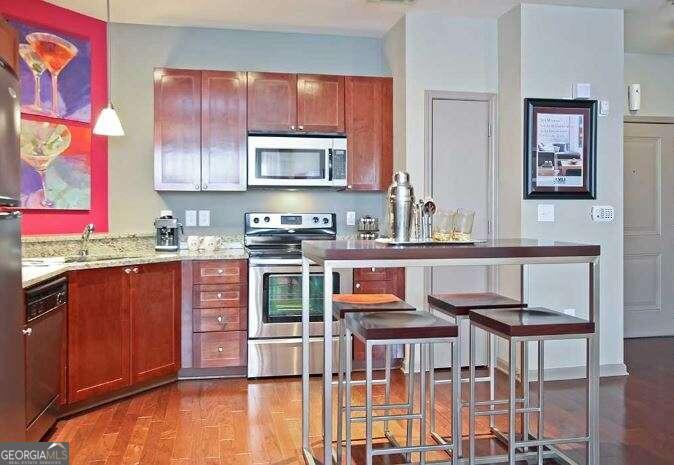 a kitchen with stainless steel appliances granite countertop a stove a sink dishwasher and cabinets with wooden floor