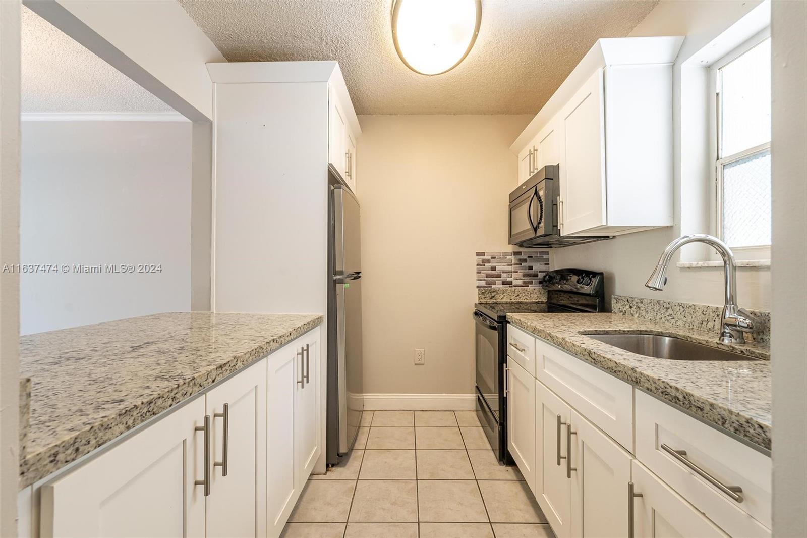 a kitchen with stainless steel appliances granite countertop a sink and a refrigerator