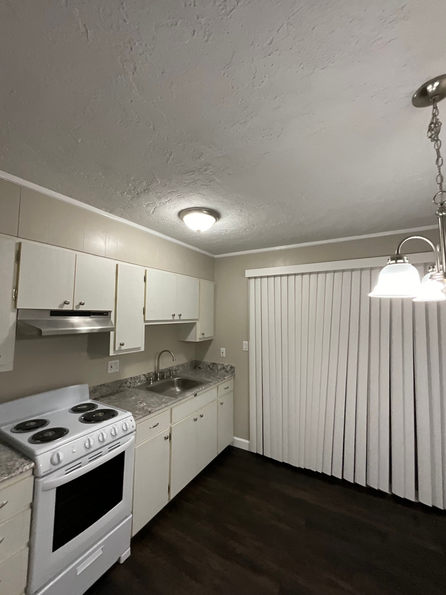 a kitchen with stainless steel appliances granite countertop a stove a sink and white cabinets