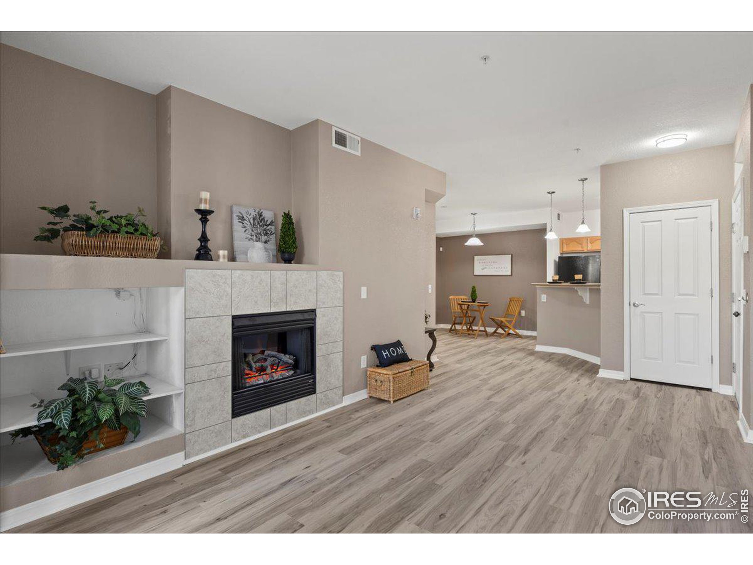 a view of an empty room with wooden floor and a fireplace