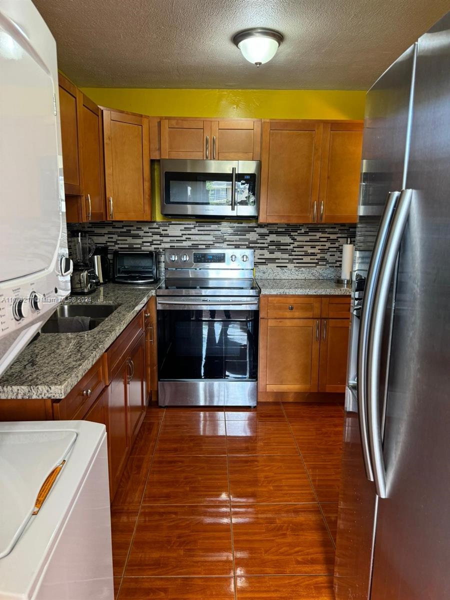 a kitchen with stainless steel appliances granite countertop a stove a sink and a microwave