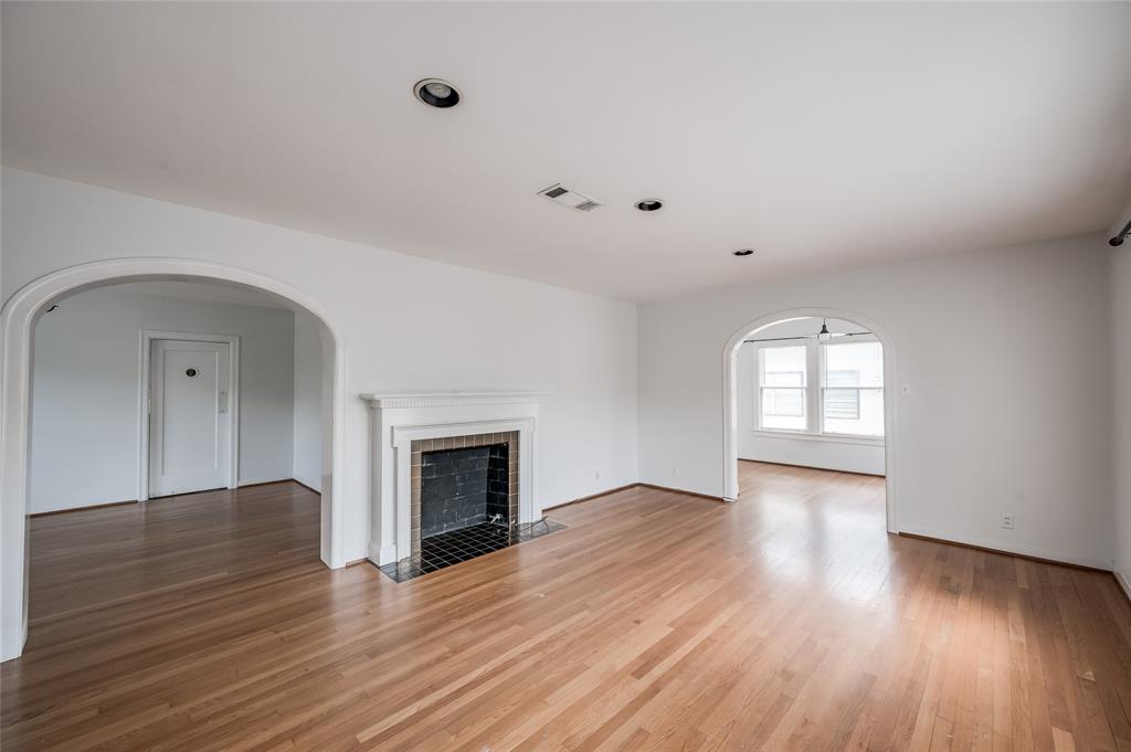 an empty room with wooden floor fireplace and windows