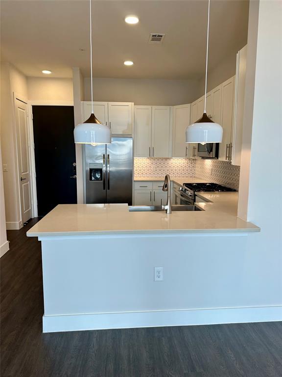 Bright and airy kitchen featuring modern quartz countertops, a designer backsplash, and chic pendant lighting.