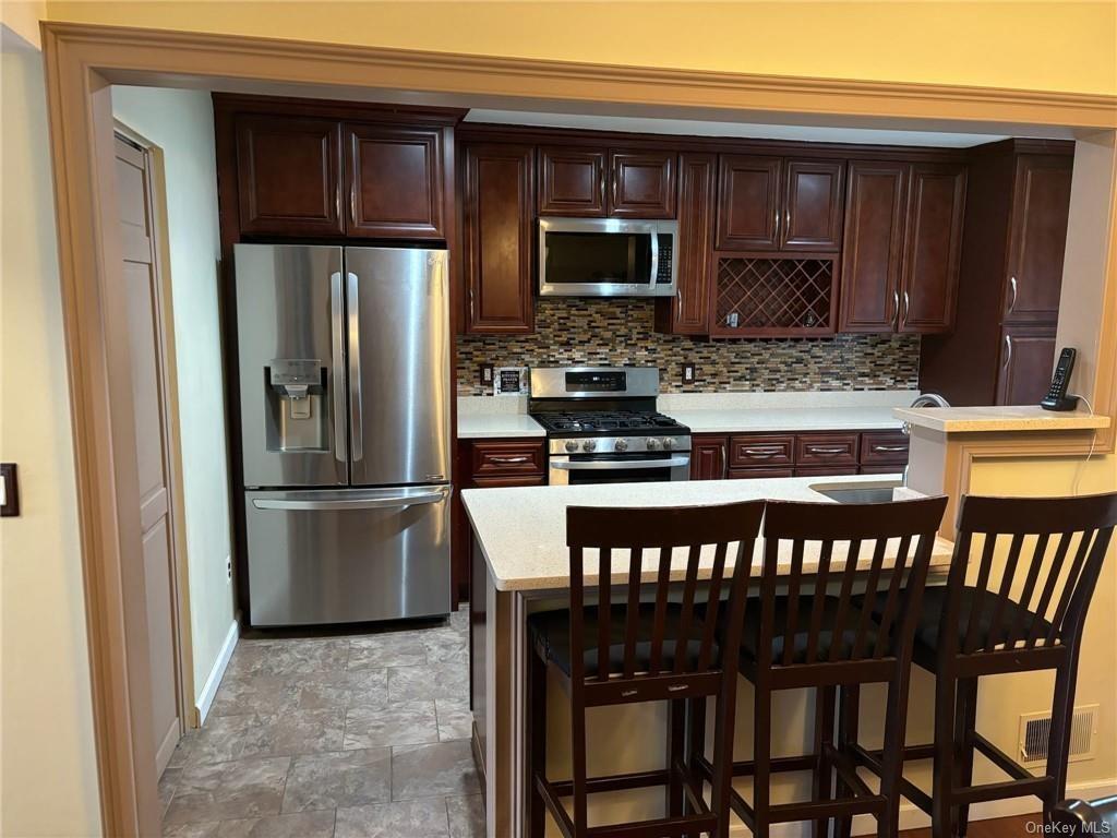 a kitchen with stainless steel appliances granite countertop a table chairs microwave and refrigerator