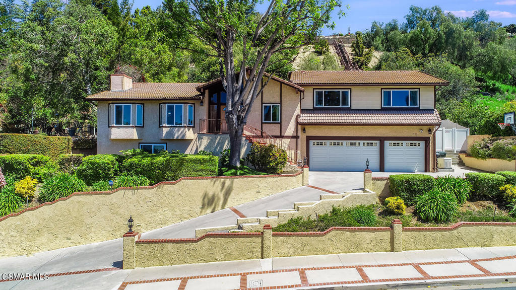 a front view of a house with garage and plants