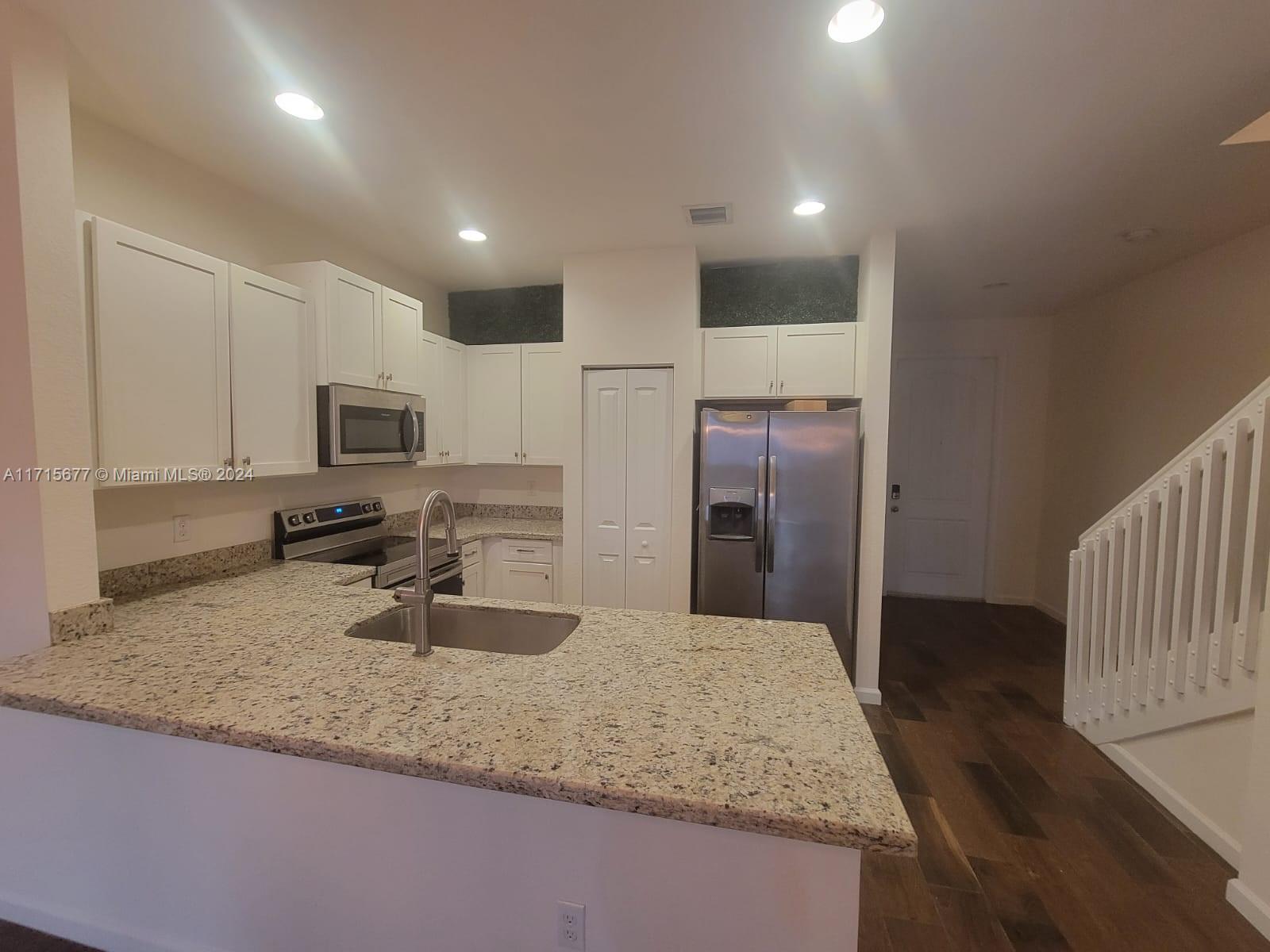 a kitchen with sink refrigerator and microwave