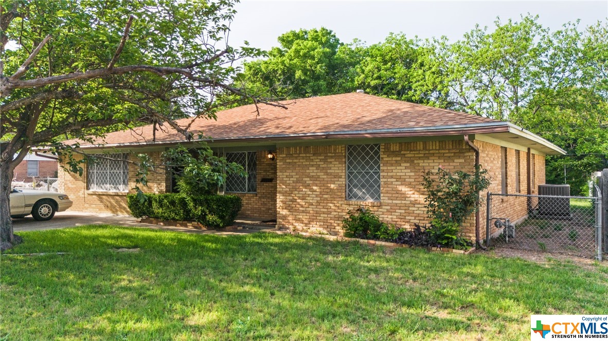 a view of a house with a yard potted plants and large tree