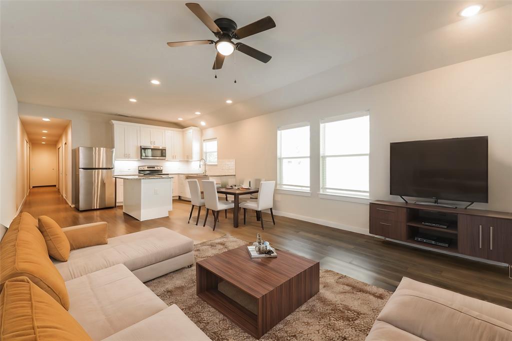 a living room with furniture and a flat screen tv with kitchen view