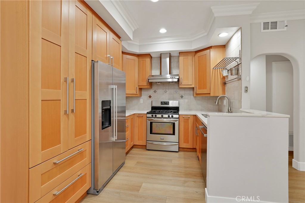 a kitchen with stainless steel appliances granite countertop a refrigerator a stove and a sink with wooden floor