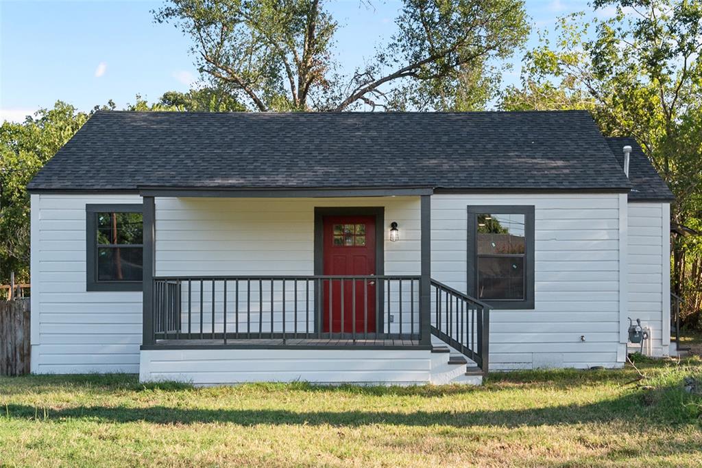 a view of a house with a small yard deck and a large tree