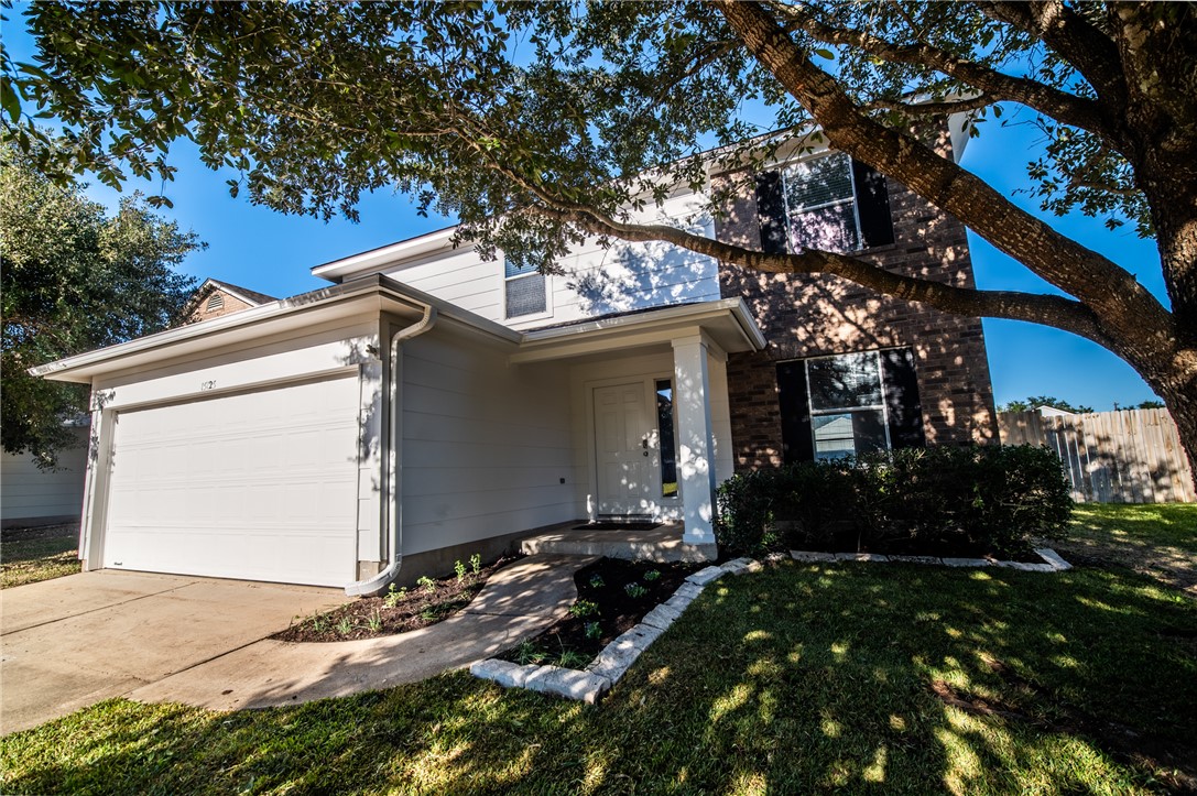 View of front of home with a front yard and a gara