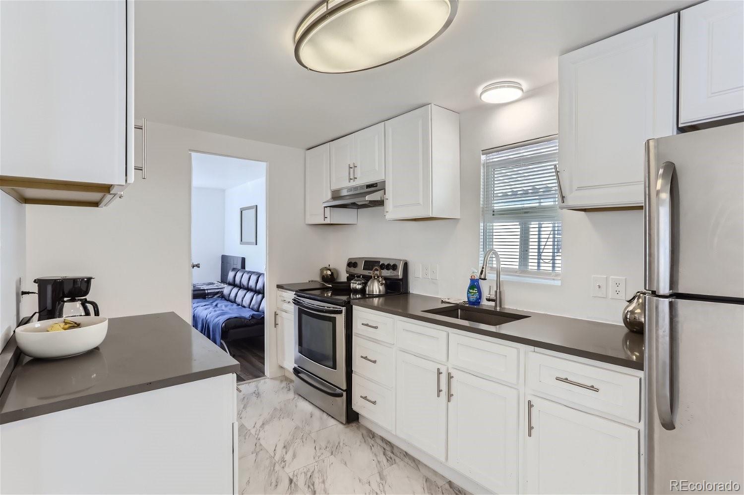 a kitchen with stainless steel appliances granite countertop a sink stove refrigerator and cabinets