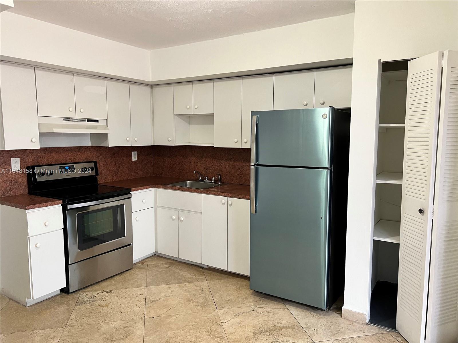 a kitchen with a refrigerator stove and white cabinets