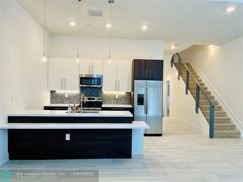 a view of kitchen with stainless steel appliances granite countertop stove top oven and cabinets