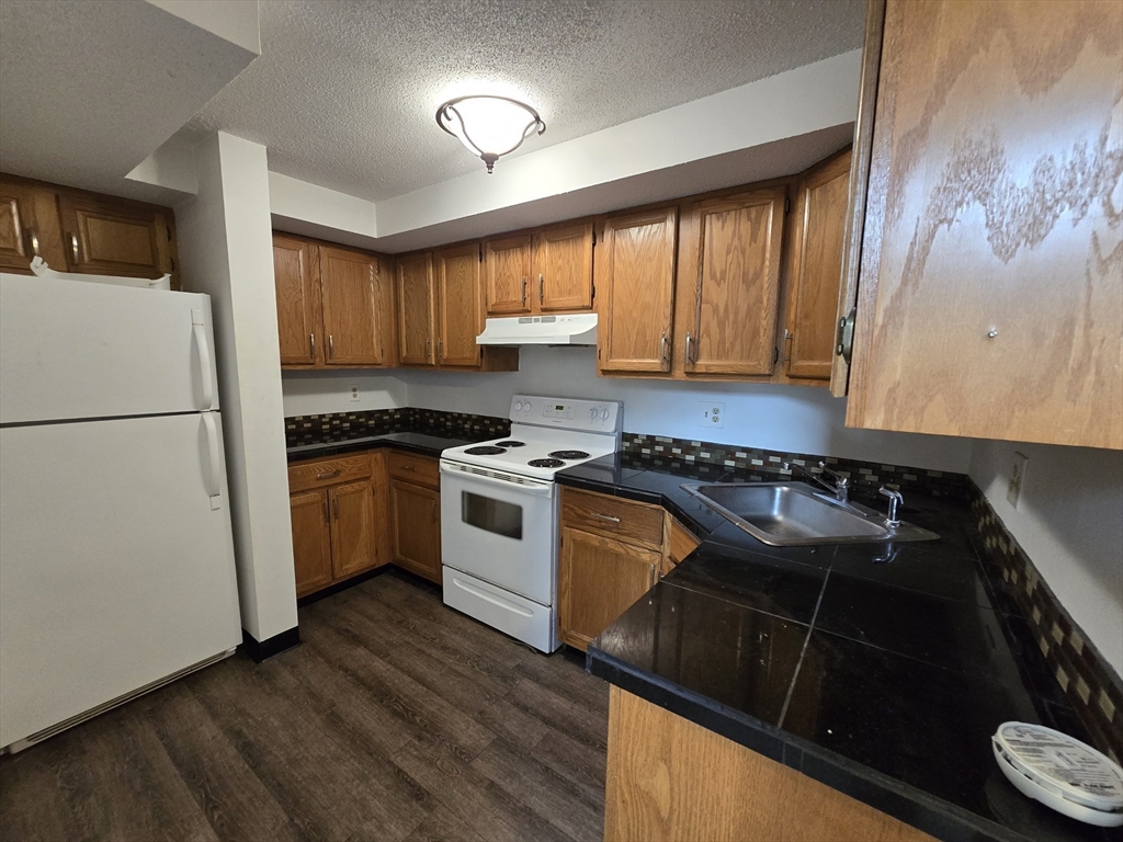 a kitchen with granite countertop a stove a sink and a refrigerator