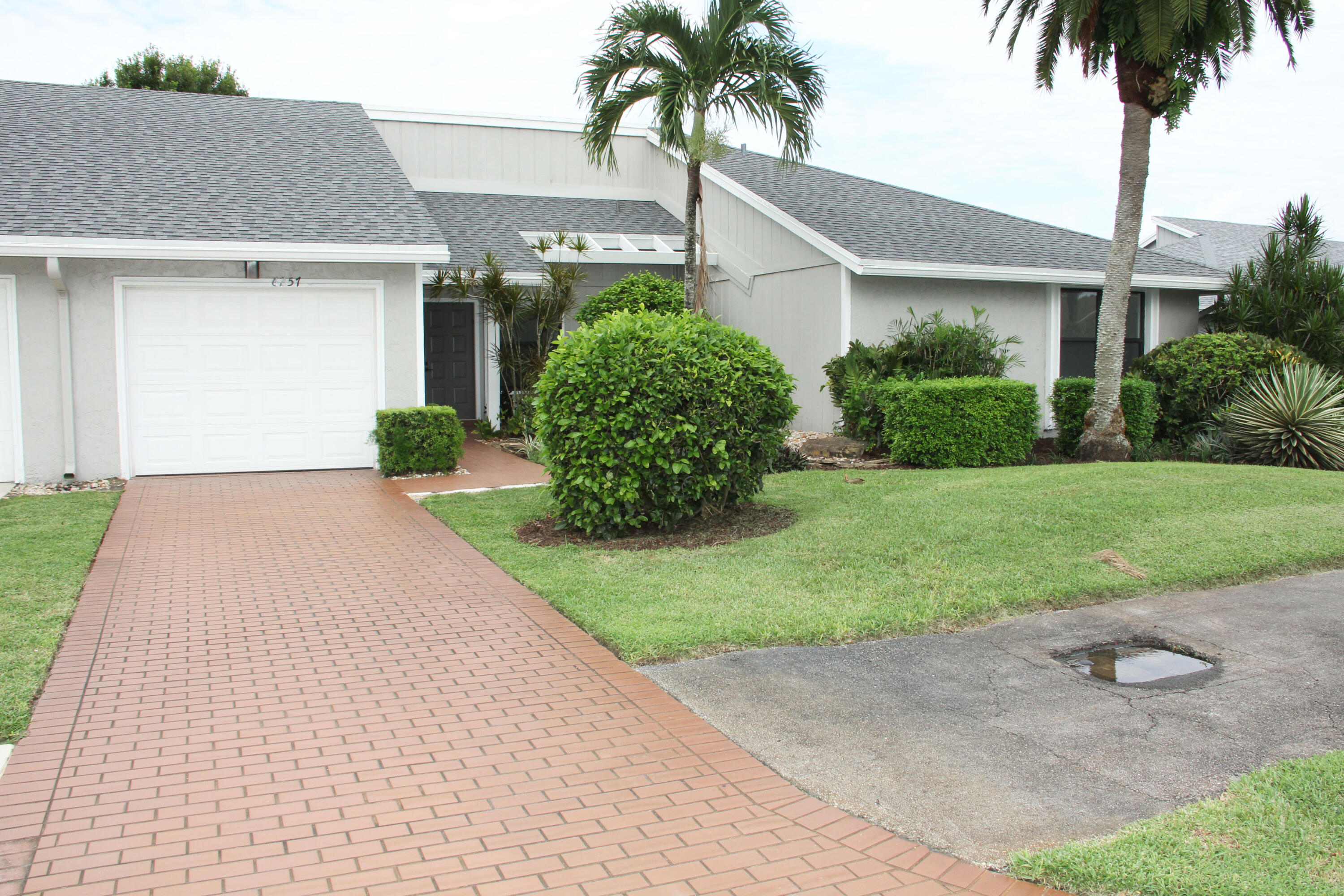 front view of a house with a yard and palm trees