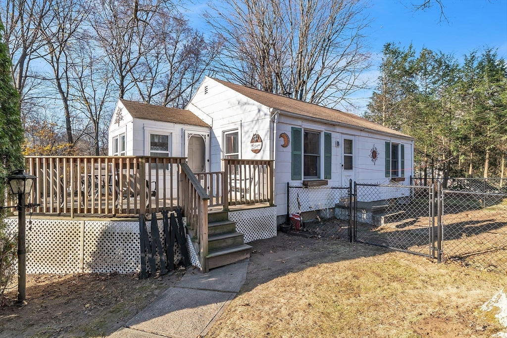 a view of a house with a wooden bench in a backyard