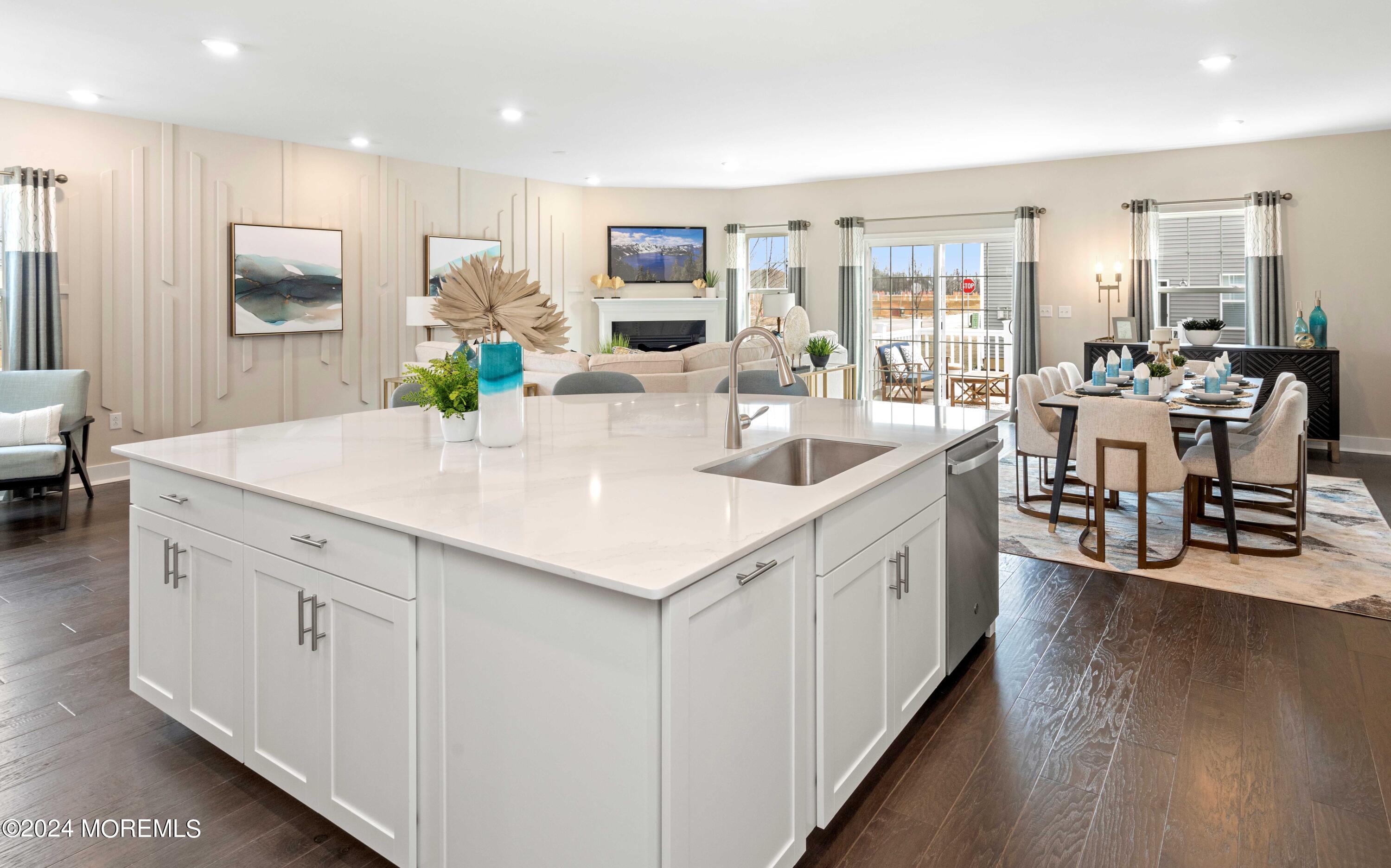 a large white kitchen with kitchen island white cabinets and wooden floor