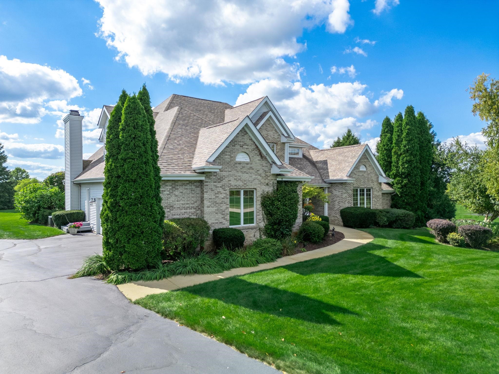 a view of a house with a big yard plants and large trees