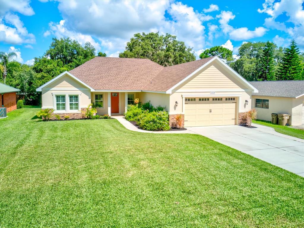 a view of a house next to a big yard and large trees