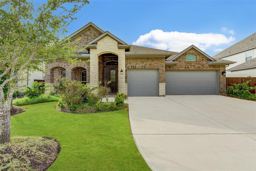 This charming brick home boasts a welcoming front porch, three-car garage, and beautifully landscaped yard. Its attractive architecture and spacious driveway enhance its curb appeal.