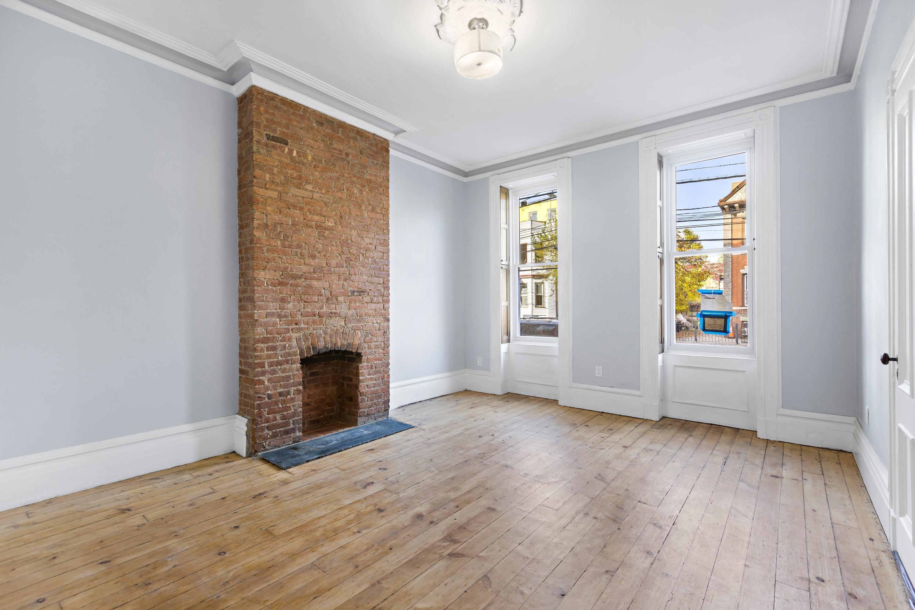 an empty room with windows a fireplace and wooden floor