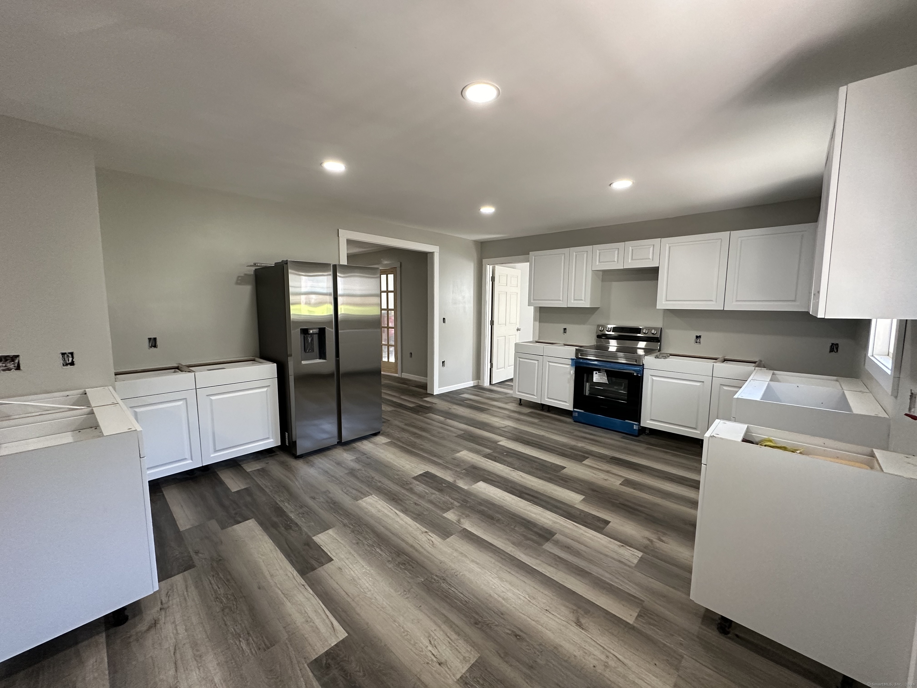 a large white kitchen with kitchen island a sink stainless steel appliances and cabinets