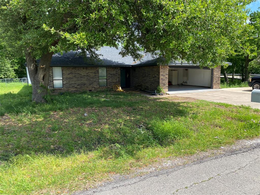 a front view of a house with a yard and a large tree