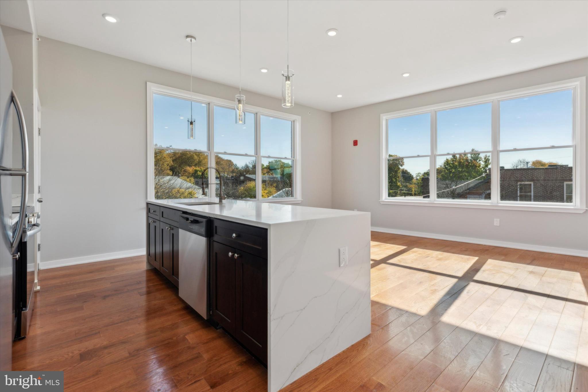 a kitchen with stainless steel appliances granite countertop a stove a sink and a refrigerator with wooden floor