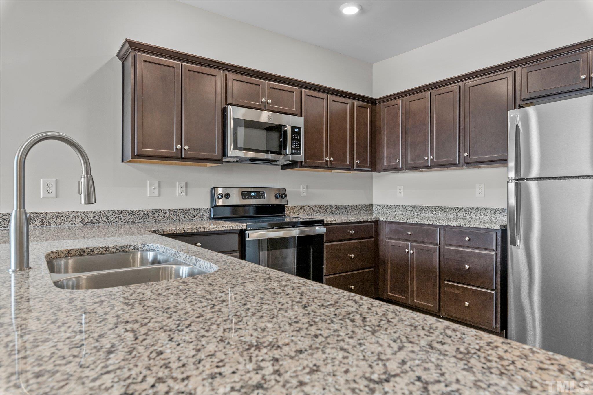 a kitchen with stainless steel appliances granite countertop a refrigerator sink and stove