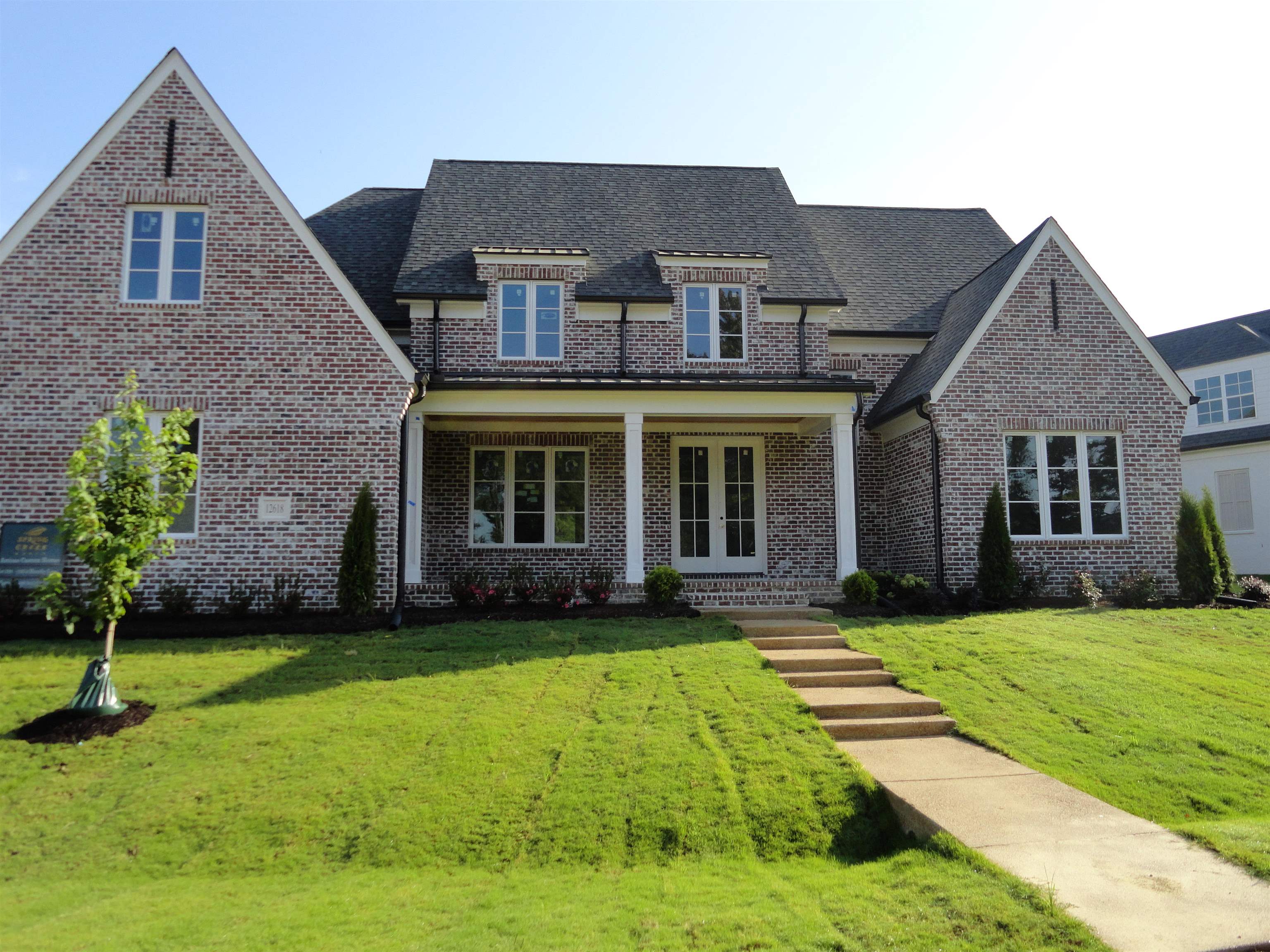 a view of a yard in front of a brick house with a large windows