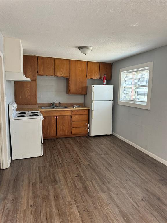 a kitchen with wooden floors and white stainless steel appliances