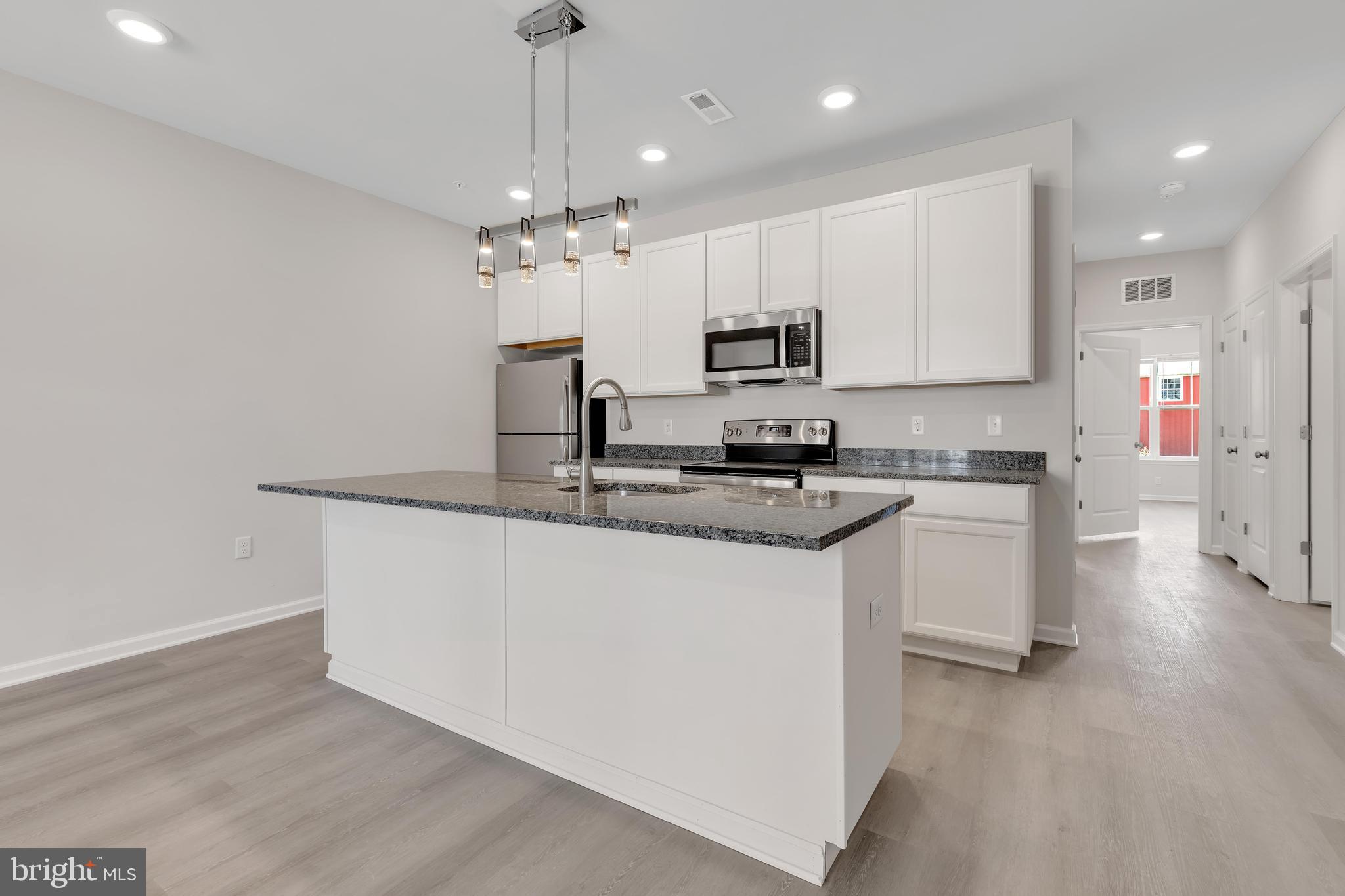 a kitchen with kitchen island granite countertop stainless steel appliances cabinets a sink and a counter top space