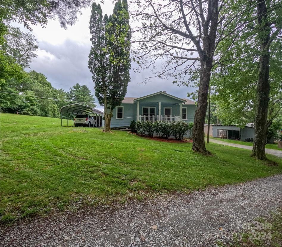 a view of house in front of a big yard with large trees