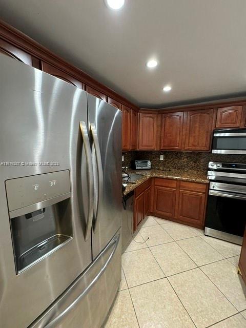 a kitchen with granite countertop a refrigerator and a stove top oven