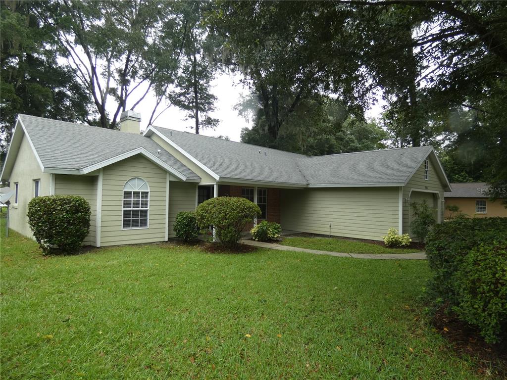 a view of a house with a yard and large trees