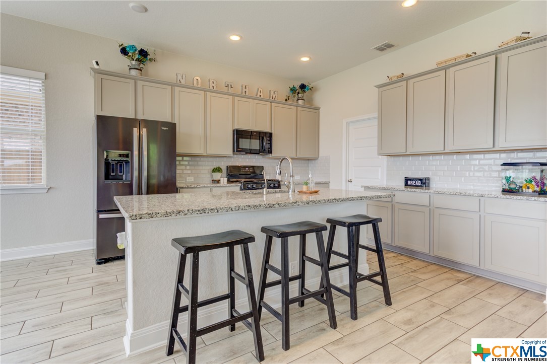 a kitchen with kitchen island granite countertop a table chairs microwave and cabinets