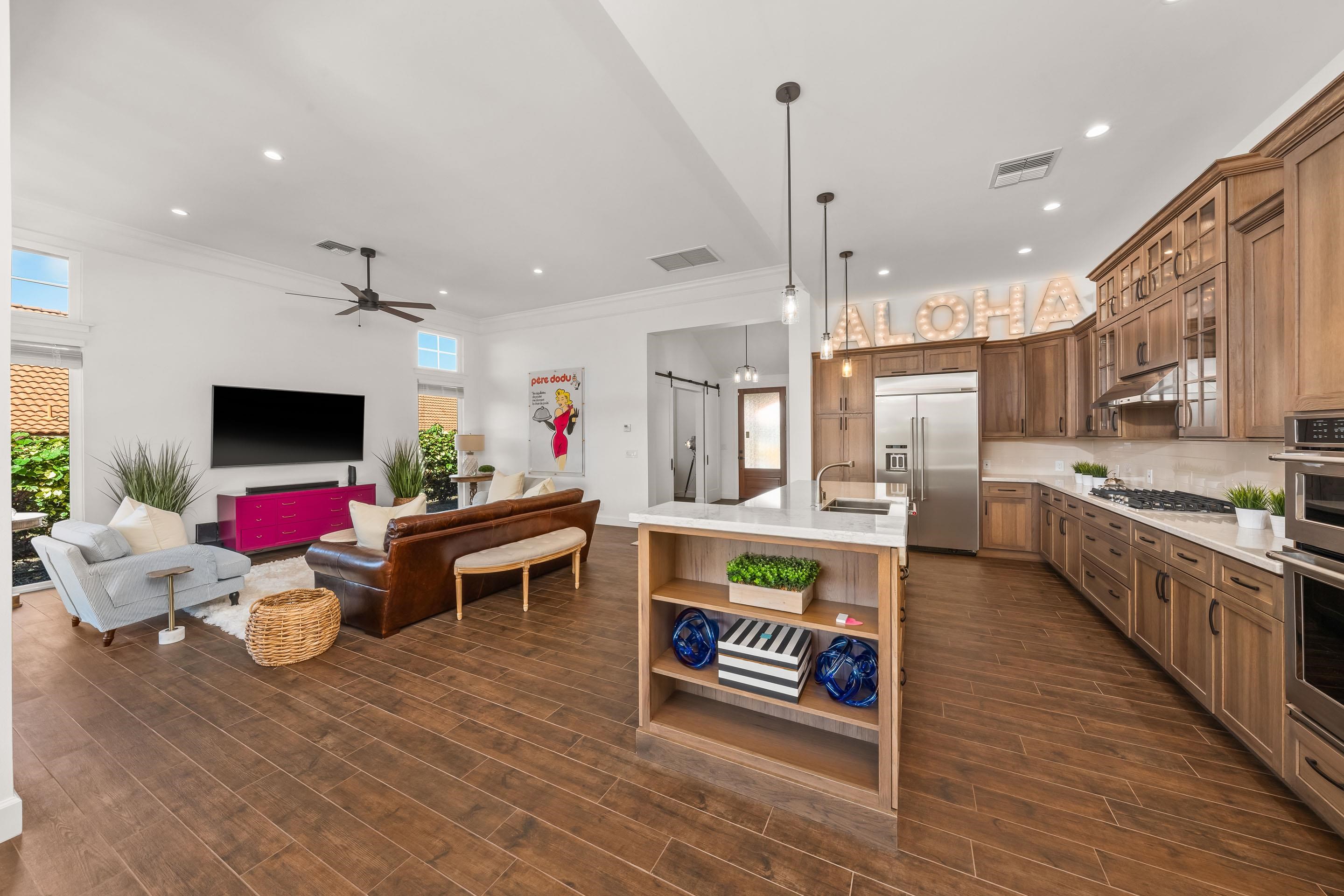 a living room with stainless steel appliances kitchen island granite countertop a couch and a wooden floor