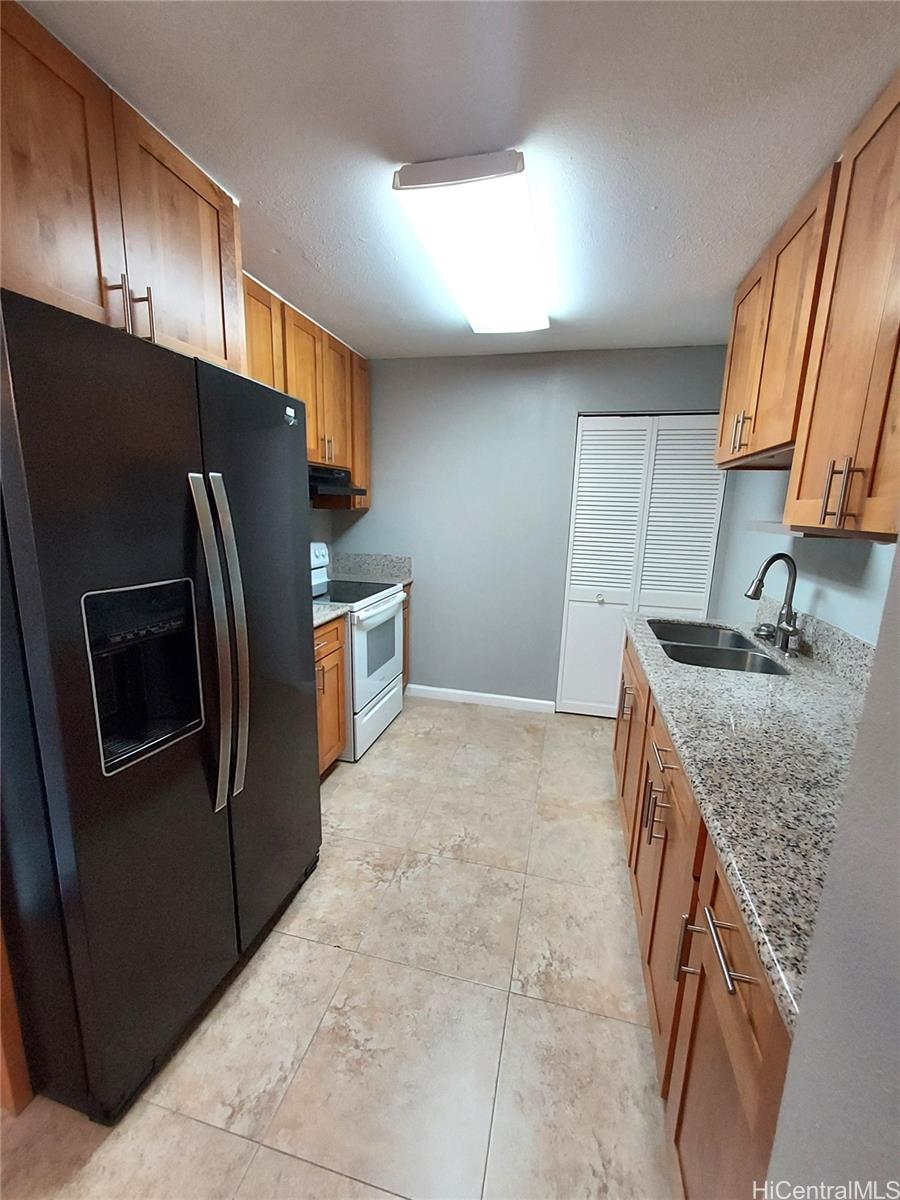 a kitchen with granite countertop a refrigerator and a sink