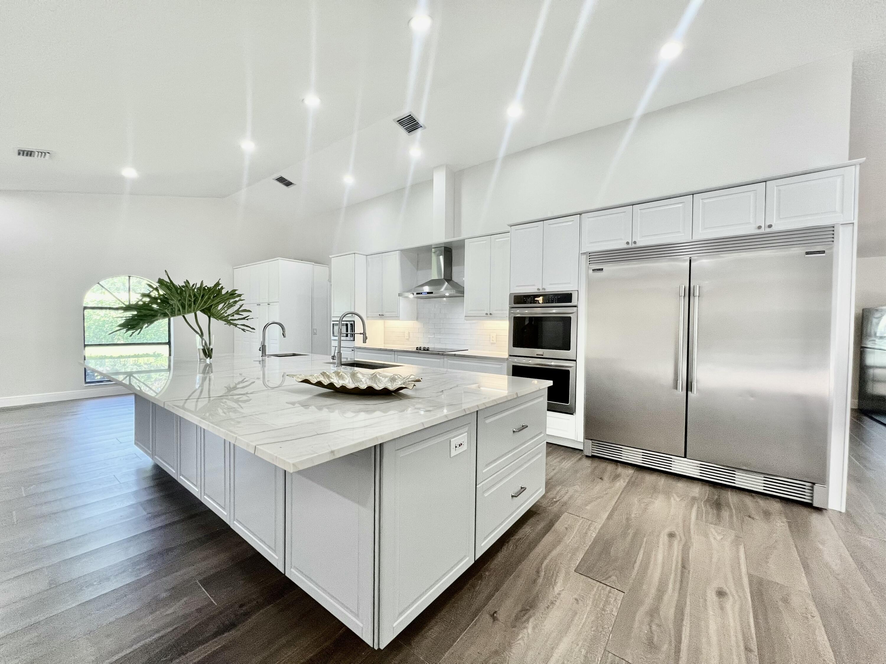 a kitchen with kitchen island white cabinets and stainless steel appliances