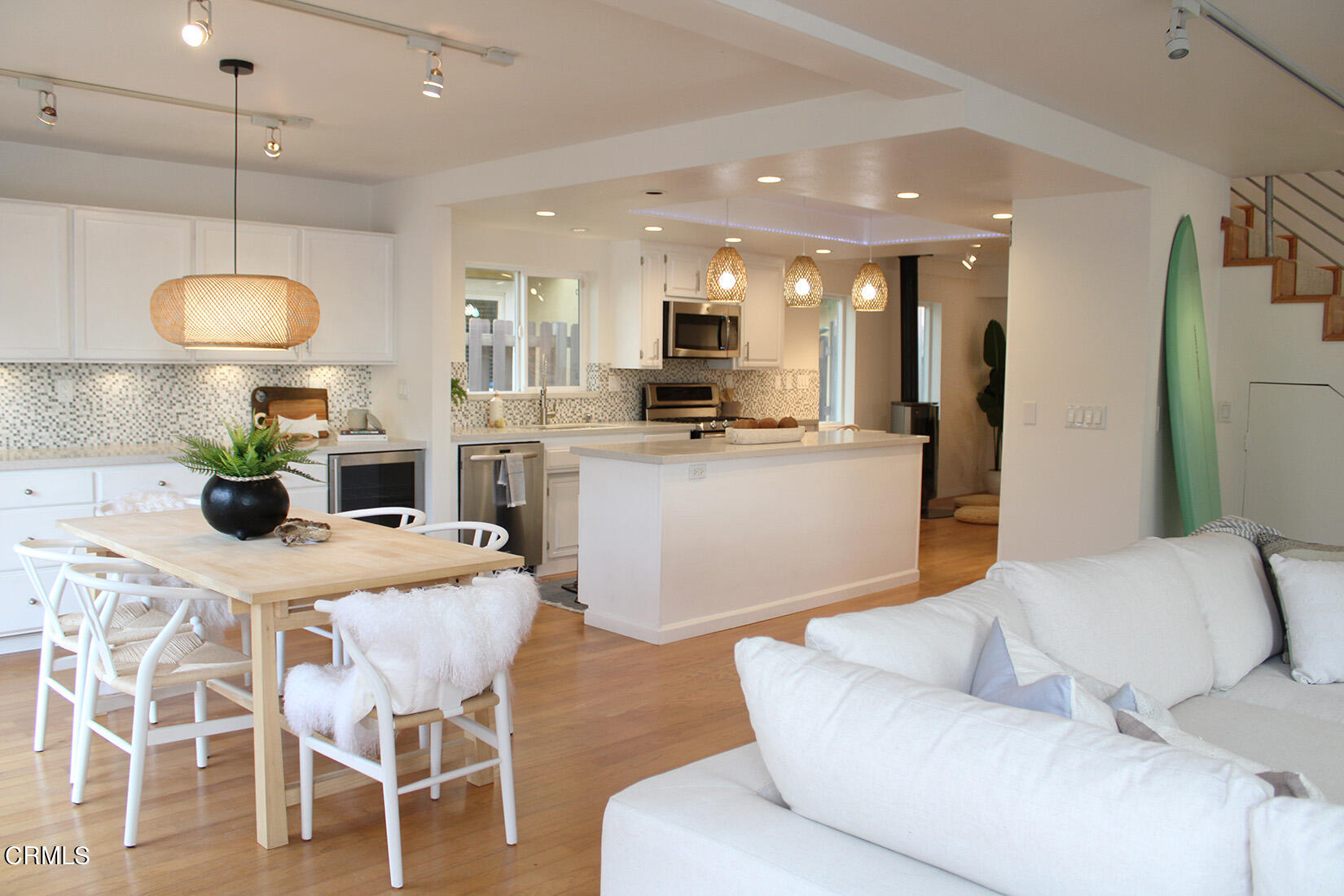 a living room with stainless steel appliances kitchen island granite countertop furniture and a wooden floor