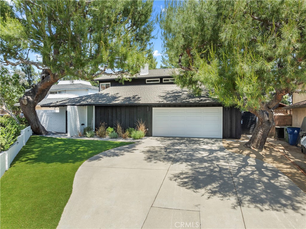 a front view of a house with a garden and tree